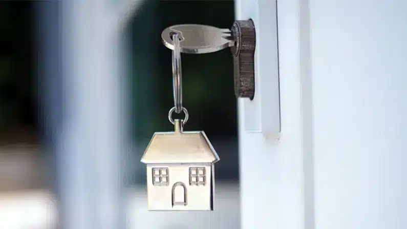 First Home Buyer Checklist with a house key in a door and a keychain with a silver little house