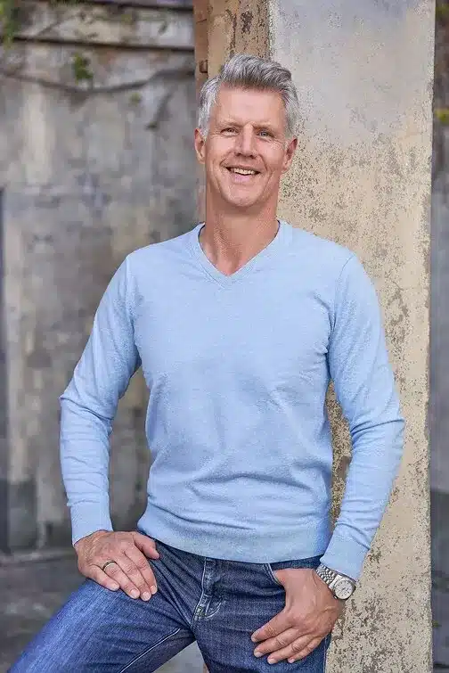 Joerg Mueller Brisbane Buyers Agent Joerg Mueller Brisbane Buyers Agent wearing a blue jumper and jeans against a wall
